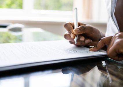 A property manager fills out legal paperwork at a glass desk.