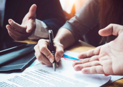 A close up of a property manager's hand writing a marketing plan for the investment property, while two other hands are pictured in motion.